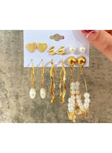 Gold-tone and pearl mixed earrings set held by a hand on card