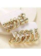 Gold hoop earrings and studs with rhinestone geometric shapes, stacked on white display