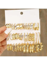 Gold-tone hoop earrings set on hanging card, shown in hand