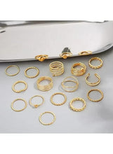 Gold tone knuckle ring set with assorted thin rings, arranged on a tray