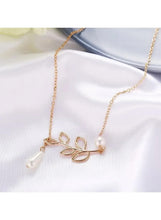 Gold leaf pendant necklace with teardrop pearl drop and butterfly-like charm