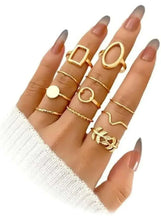 Gold-tone geometric ring set worn on hand, square and oval top rings with slim bands.