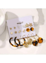 Earring set on display card with gold-tone studs, pearl-like pieces, and amber tortoise hoops
