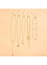 Gold tone necklace set with multiple chains and star, heart, and pearl charms