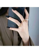 Gold-tone rings on finger, including a chain-link band and a slim plain band
