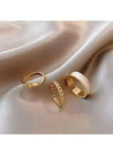 Gold-tone and white enamel rings with cutout settings and a small chain-link band