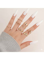 Gold plated women’s ring set displayed on a hand with long white nails and a gray sweater