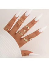 Gold-tone plated ring set on hand with patterned band and charm-stone ring