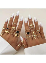 Gold-tone mixed ring set on hands, long white nails, black and heart designs