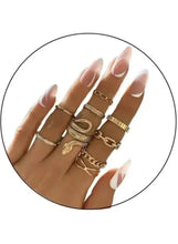Gold snake & chain ring stack on hand: nine linked and textured bands