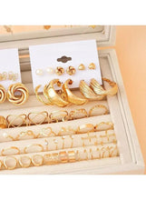 Gold-tone swirl and hoop earrings with matching rings in a jewelry box tray
