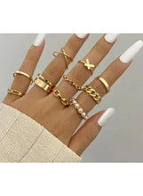 Gold-tone ring set on hand with pearl ring and butterfly charm, mixed band styles