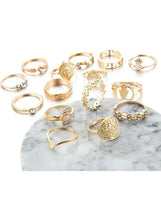 Gold-tone ring set with multiple bands and charms on a marble slab