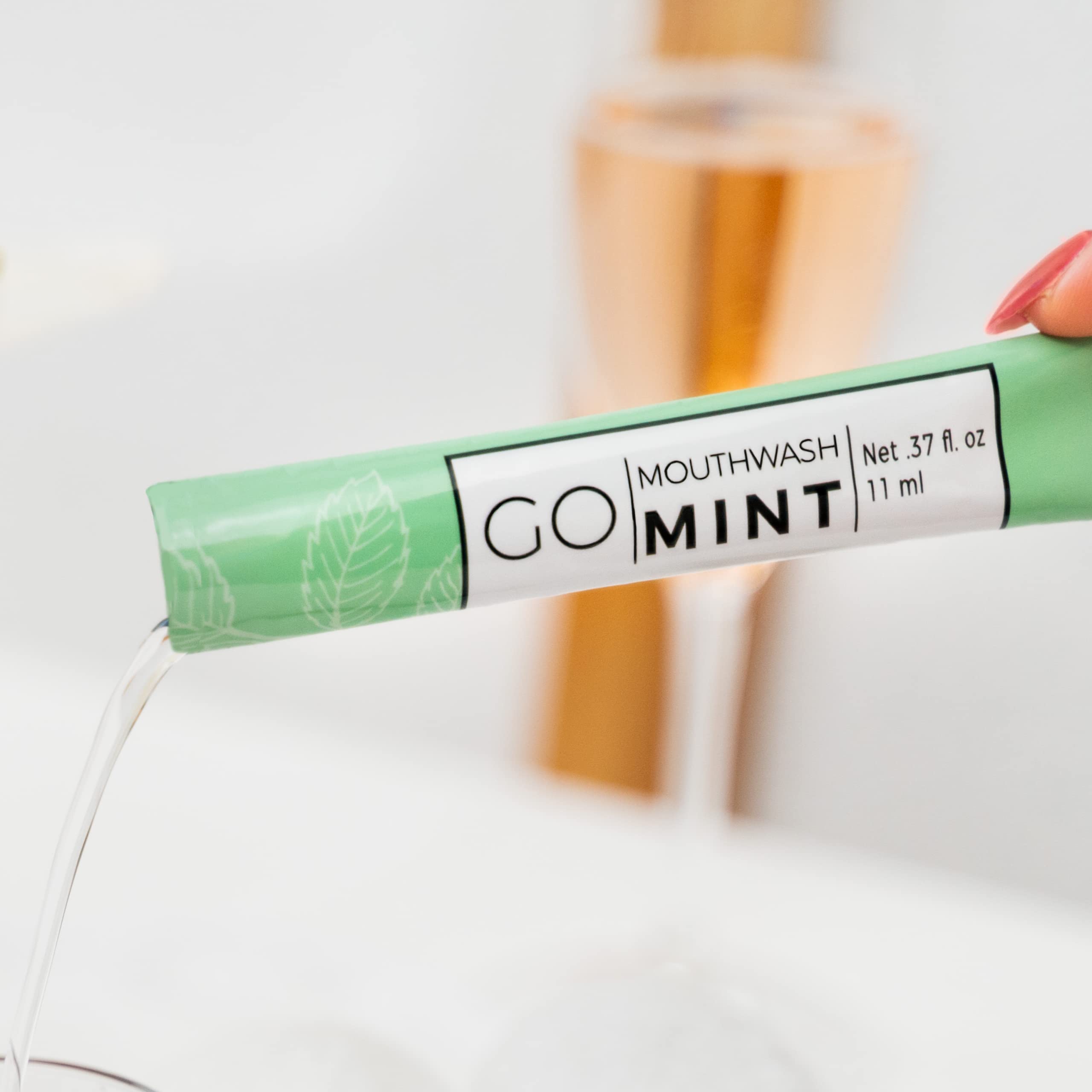 Go Essentials mint sachet labeled GO MINT pouring mouthwash into a glass travel mouthwash packets for fresh breath
