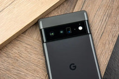 Google Pixel 6 Pro 5G unlocked black phone showing rear camera bar and G logo on wooden surface