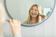 Toothbrush being used to brush teeth, teal handle and white bristles visible.