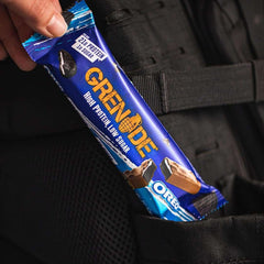 Hand placing grenade oreo protein bar in backpack pocket showing blue Grenade packaging and Oreo pieces
