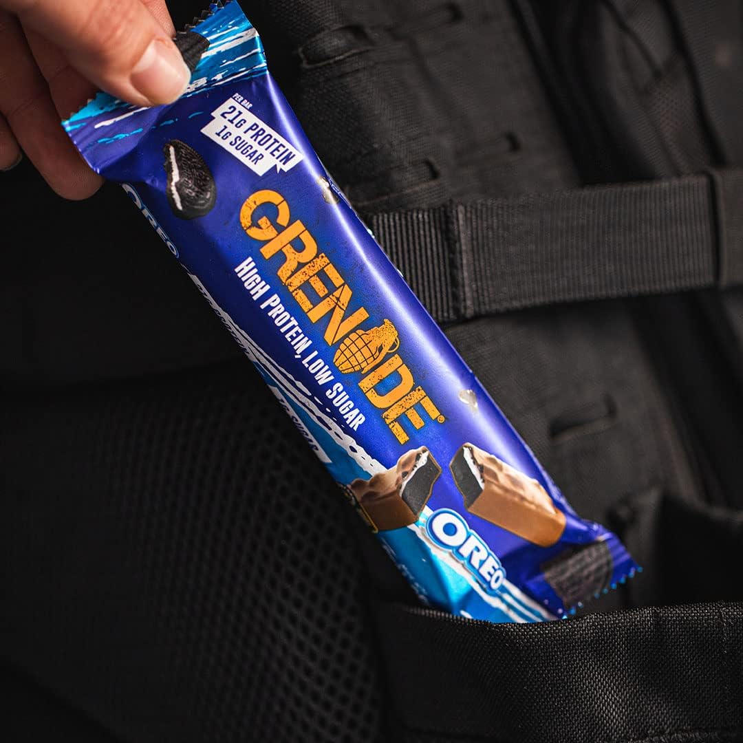 Hand placing grenade oreo protein bar in backpack pocket showing blue Grenade packaging and Oreo pieces
