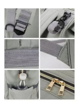 Grey baby travel backpack detail: webbing strap, zipper pulls, and metal clips
