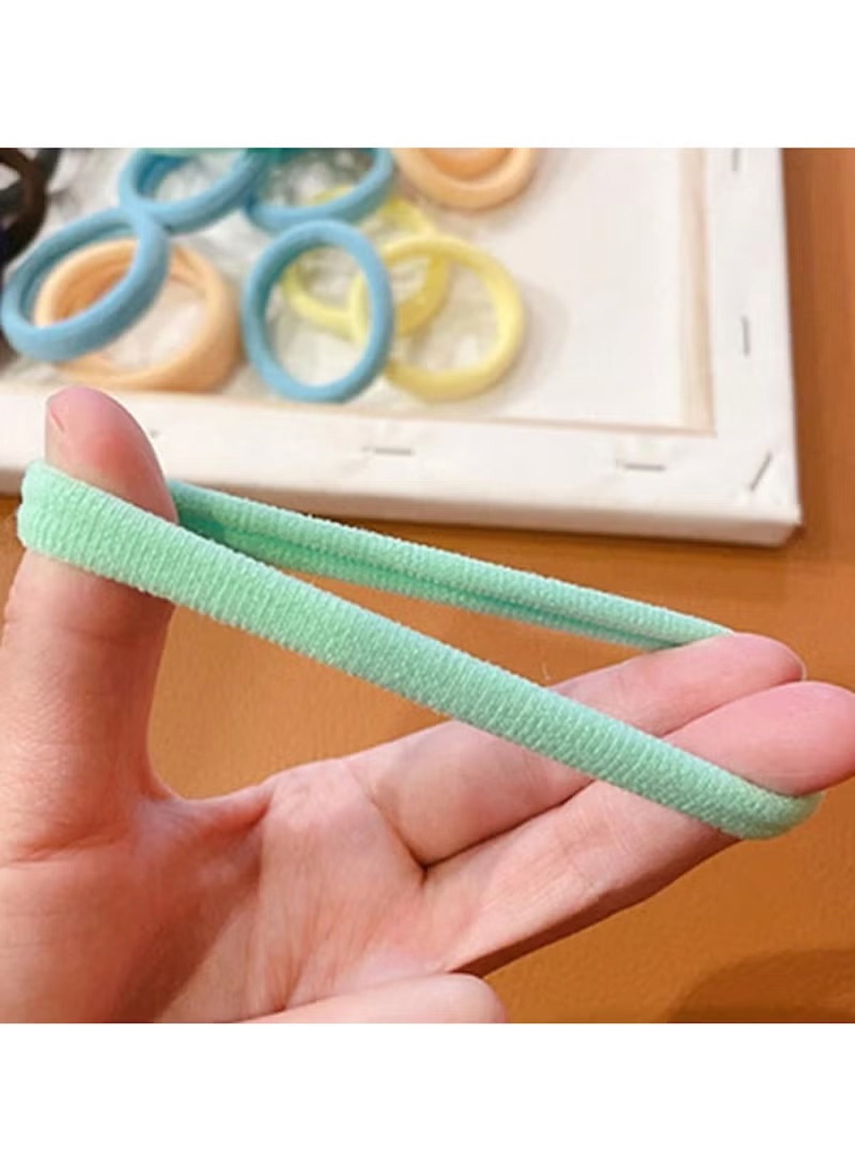 Huitich hair ties for thick hair pack of 20 showing a close-up of a green stretchy band held between fingers