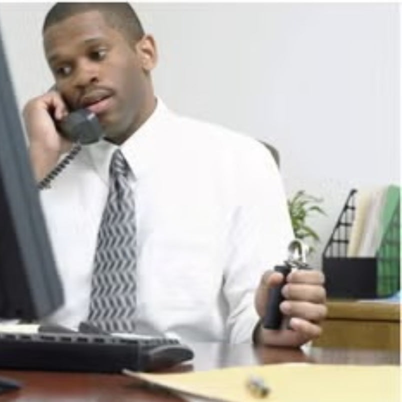 Man in office using a hand grip strengthener while talking on the phone at his desk