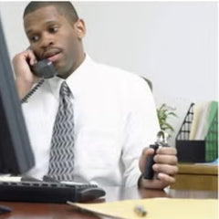 Man in office using a hand grip strengthener while talking on the phone at his desk