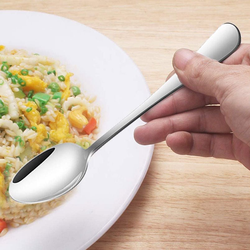 Huitich 12 piece cutlery set featuring a stainless steel spoon held over a plate of mixed rice and vegetables
