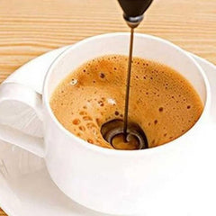 White coffee cup filled with coffee being blended using a handheld mixer for baking by Huitich