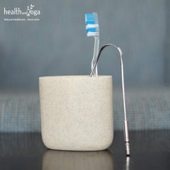 HealthAndYoga metal tongue cleaner stainless steel tongue scraper next to toothbrush in stone holder for oral hygiene