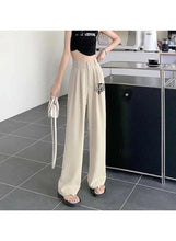 Beige high-rise pants with pleated waist, relaxed wide legs, and straight hem
