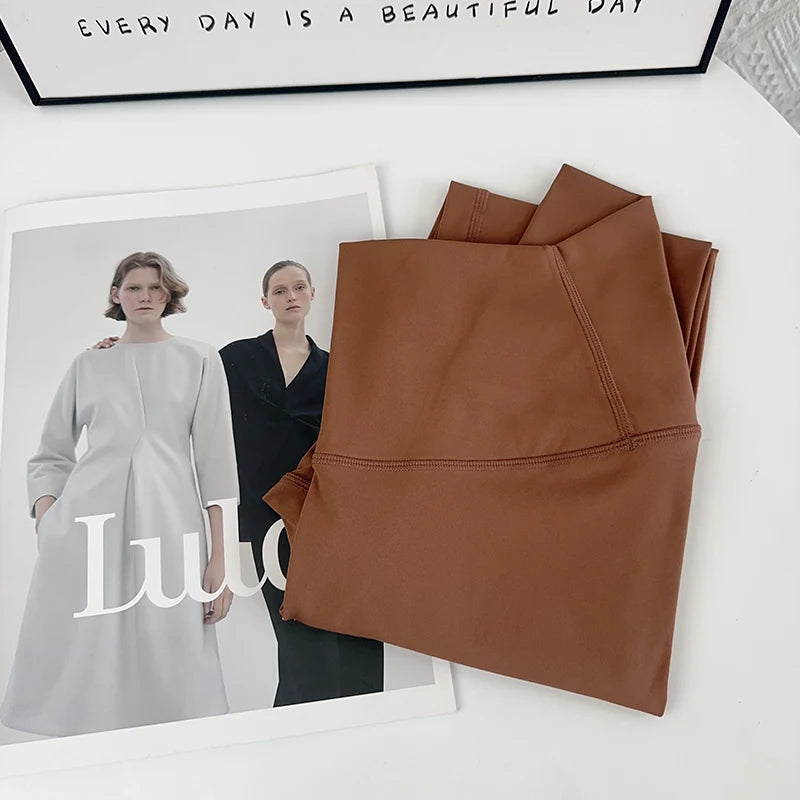 Mumzar high waist yoga leggings UAE in a stylish brown color, folded neatly on a magazine