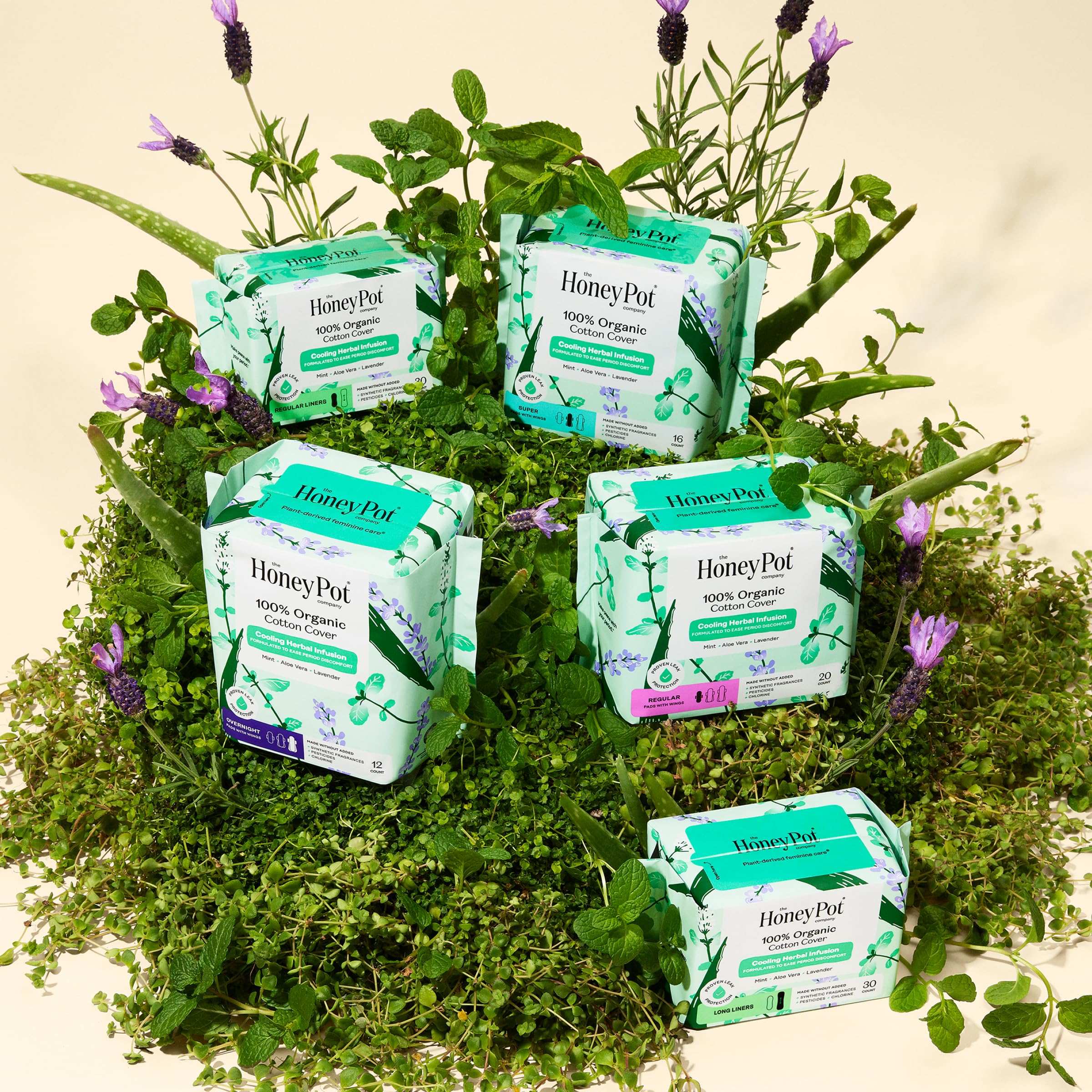 Multiple The Honey Pot herbal infused overnight menstrual pads packages displayed on greenery and lavender
