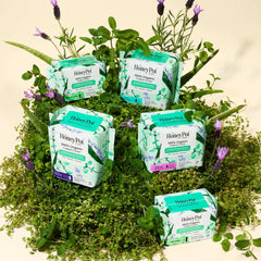 Multiple The Honey Pot herbal infused overnight menstrual pads packages displayed on greenery and lavender