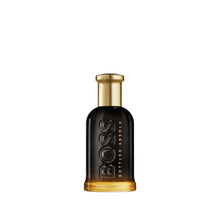 Perfume bottle with dark glass and gold cap, embossed logo on front