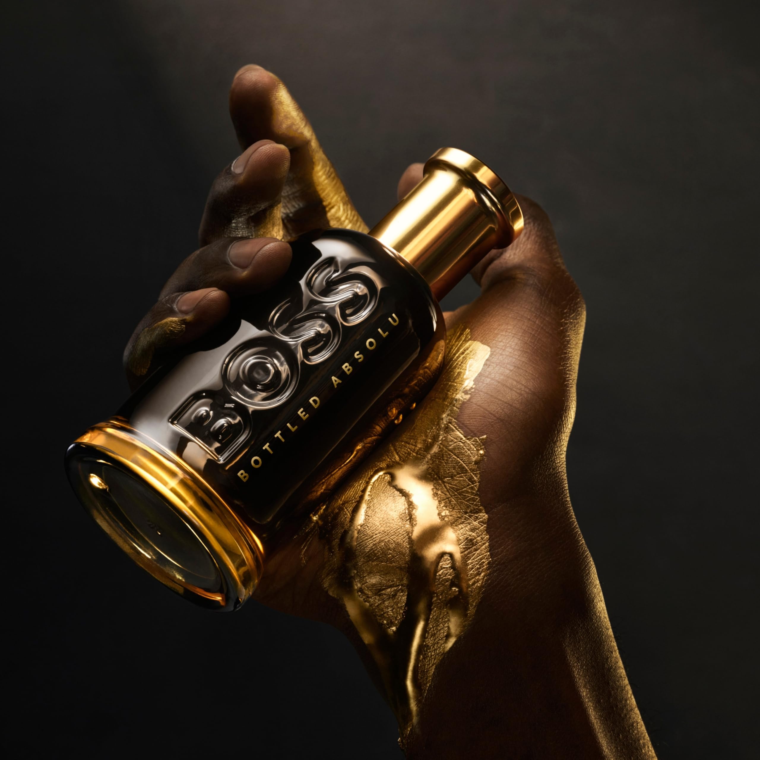 Hugo Boss Bottled Absolute Parfum Intense 3.3 oz. elegantly held in a golden hand with a dark background