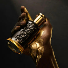 Parfum bottle in hands, black glass with gold cap and embossed BOSS logo.
