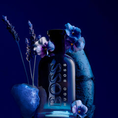 Hugo Boss Eau De Toilette 100ml price displayed on dark bottle with blue flowers and artistic background