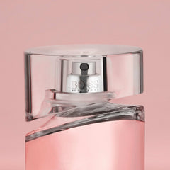 Close-up of Hugo Boss Femme perfume bottle with pink liquid and clear cap on pink background