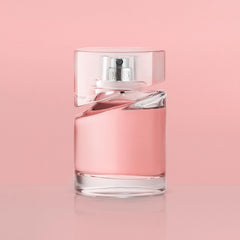 Clear glass bottle of Hugo Boss Femme perfume with pink fragrance against a soft pink background