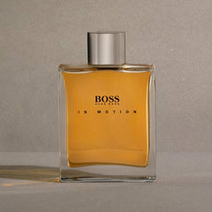 Hugo Boss In Motion for men fragrance bottle with amber liquid and silver cap on gray background