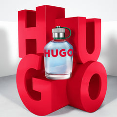 Hugo Boss Man fragrance for men bottle with blue liquid displayed on large red letters spelling HUGO