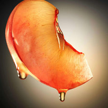Red-orange perfume liquid splash with glossy droplet tips