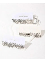 Silver-tone mix of cuff, hoop, and stud earrings set on a white display