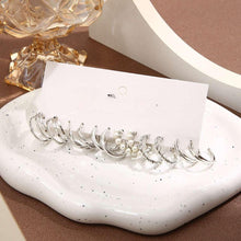 Silver-tone hoop earrings with pearl accents and small charms arranged on a card