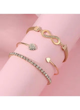 Wrist wearing gold-tone bracelet set with crystal tennis band, infinity and heart charms