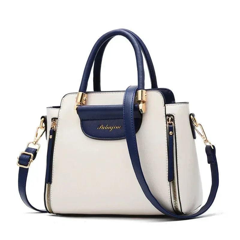 White color block shoulder bag with navy top flap, navy shoulder straps, and gold hardware