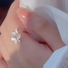 Crystal butterfly ring on hand, silver-tone band with two butterfly stone accents