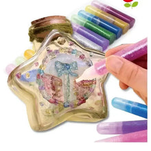 Glitter glue tubes applying sparkle to a clear craft tray with heart-shaped design