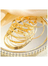 Gold tone stacked bangles with mesh-like textured bands and small ball charms