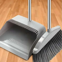 Gray dustpan with toothed rim and long-handled broom with dark bristles.